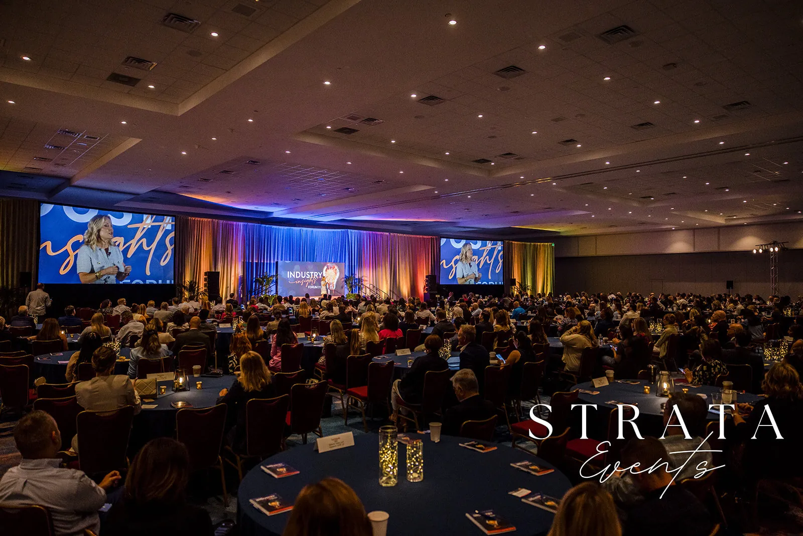 Wide Orlando event photography of a corporate general session ballroom with attendees seated and a branded stage
